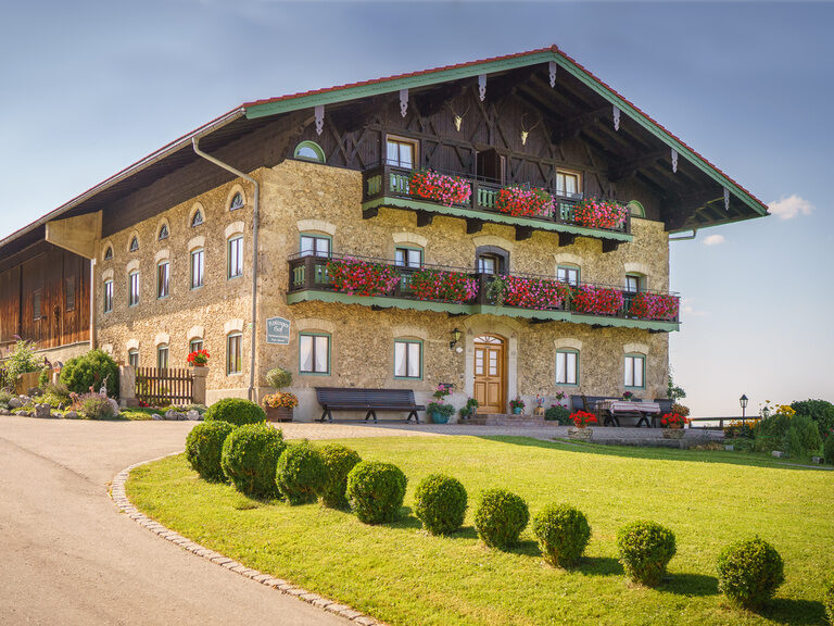 Das große Hauptgebäude wird an einem Sommertag von der Sonne angestrahlt und führt zu Bauernhoffeeling.