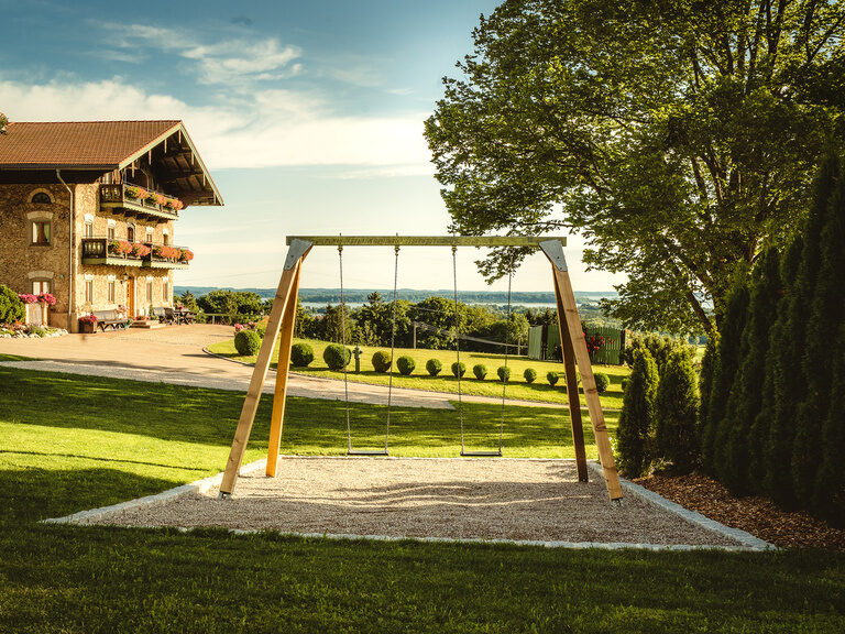 Eine Schaukel steht im Garten des Bauernhofs in Oberbayern am Chiemsee